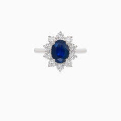 Klassischer Damenring aus 18 Karat Weißgold mit einem blauen Saphir im Ovalschliff und einem Halo aus Diamanten im Brillantschliff.