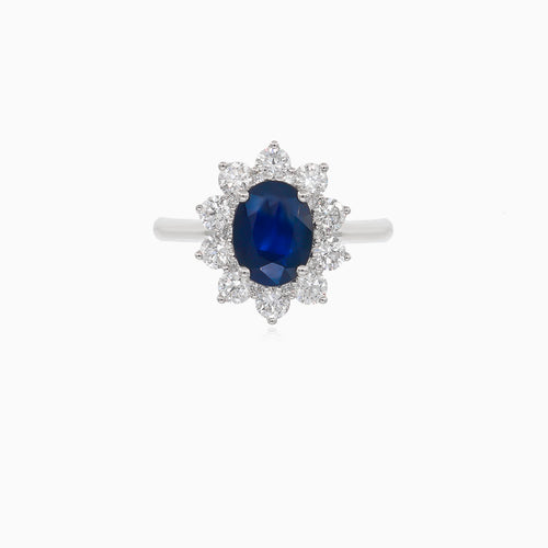 Klassischer Damenring aus 18 Karat Weißgold mit einem blauen Saphir im Ovalschliff und einem Halo aus Diamanten im Brillantschliff.