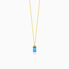 A beautiful gold necklace with a synthetic sapphire pendant