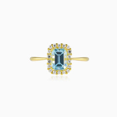 Halo-Ring aus Gold mit blauem Topas im Smaragdschliff