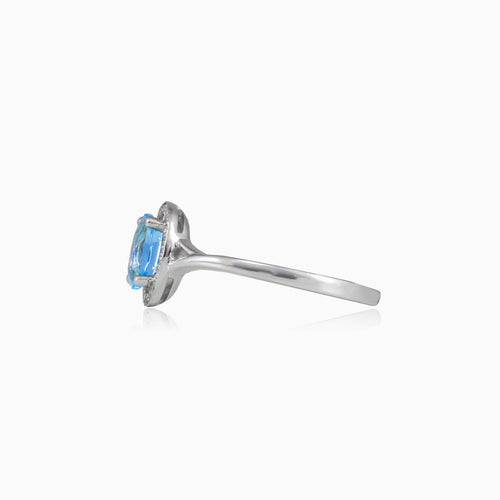 White gold ring with blue topaz and diamond halo design