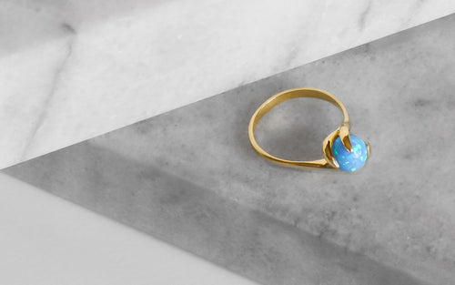 Prsten ze žlutého 14kt zlata v kombinaci s modrým kulatým opálem.