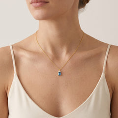 A beautiful gold necklace with a synthetic sapphire pendant