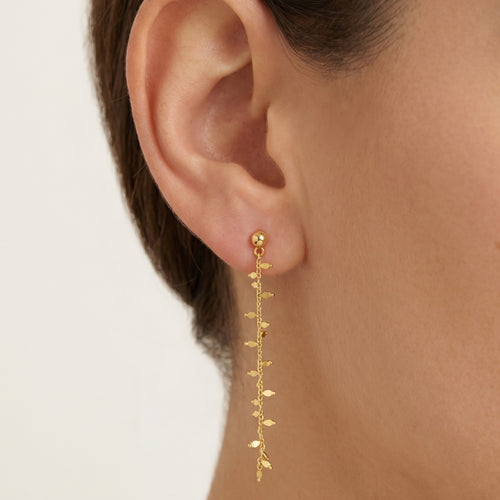 Gold earrings hanging with leaves