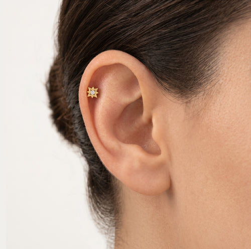Gold compas ear piercing