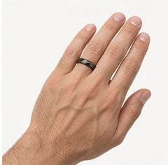 A close-up of a person's hand wearing a slim dark metallic band ring, shown against a clean off-white background.