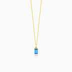 A beautiful gold necklace with a synthetic sapphire pendant